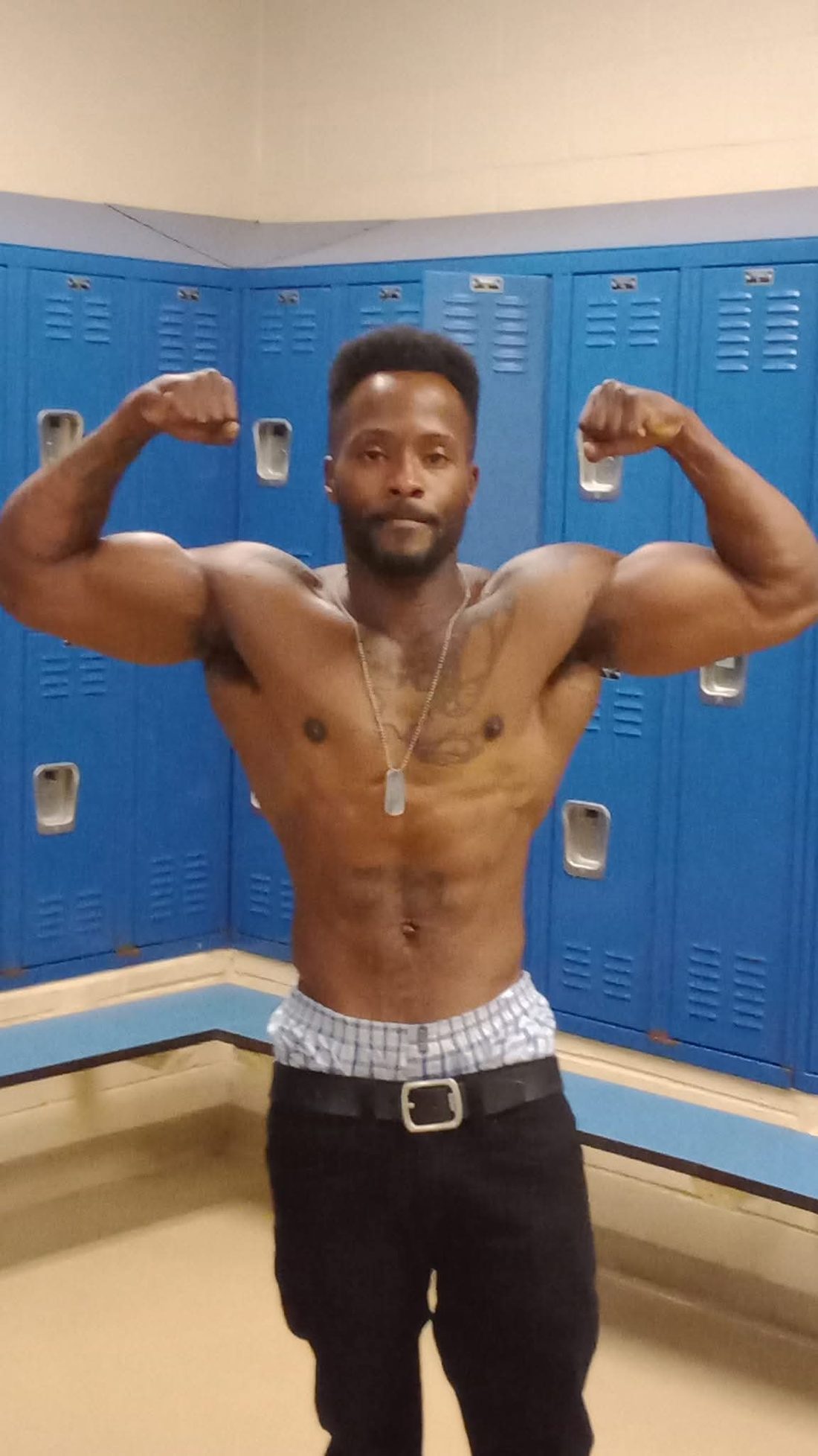 Tony Bess, founder and trainer at Faith and Fitness Academy, flexing in the locker room